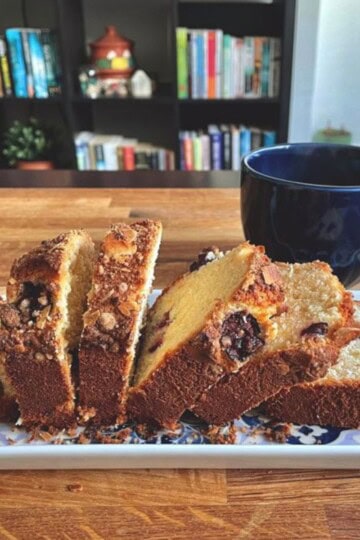 Delicious cherry loaf cake slices with a cup of tea on a wooden table.