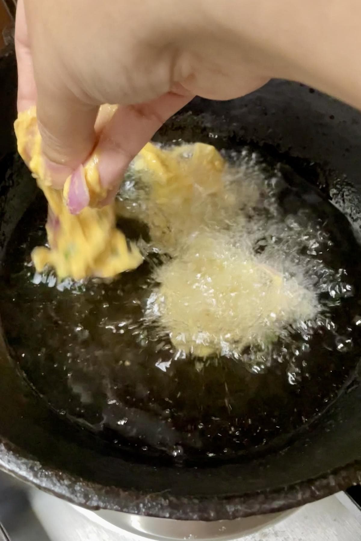 Dropping a spoonful of hand picked dough into the hot oil.