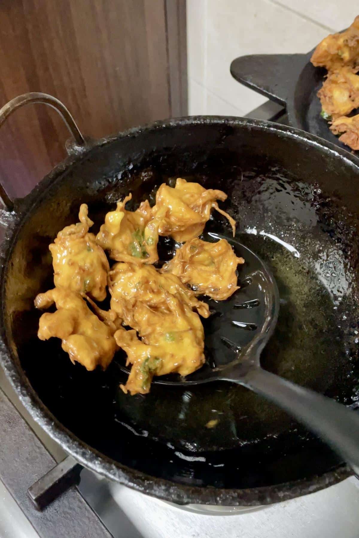 Crispy onion pakoda removed using slotted spoon.