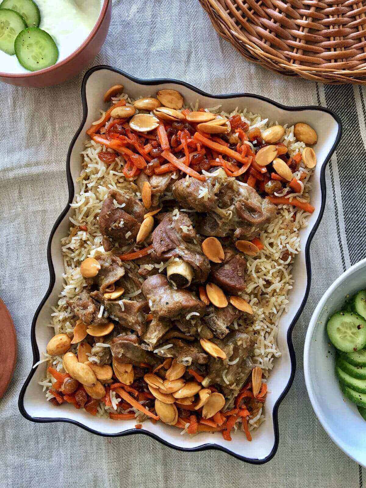 a rectangular serving dish filled with rice and topped with pieces of lamb meat.