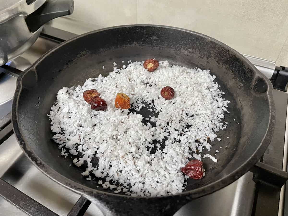 Grated coconut with dried rec chillies in a cast iron skillet. 