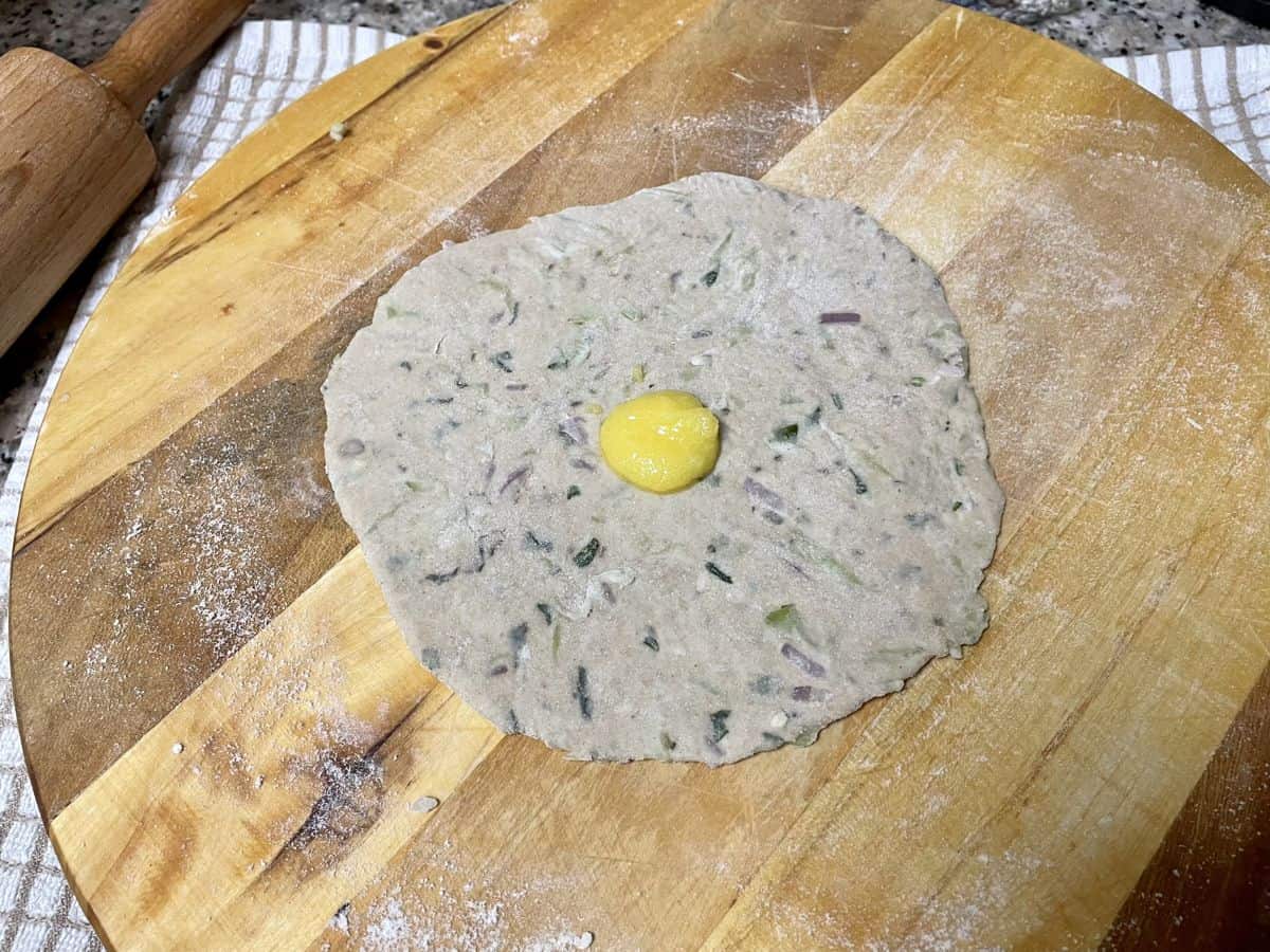 Rolled out dough ball to flatbread with a knob of ghee on it.