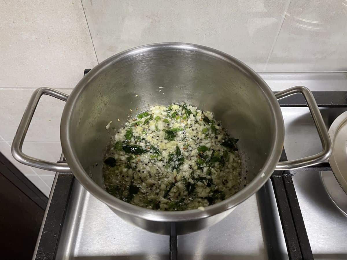 Sauteing the aromatics for lime pickle in a steel pot. 