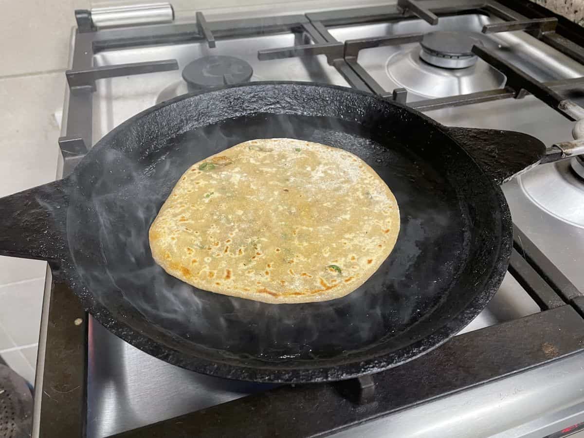 Cooking paratha on hot pan.