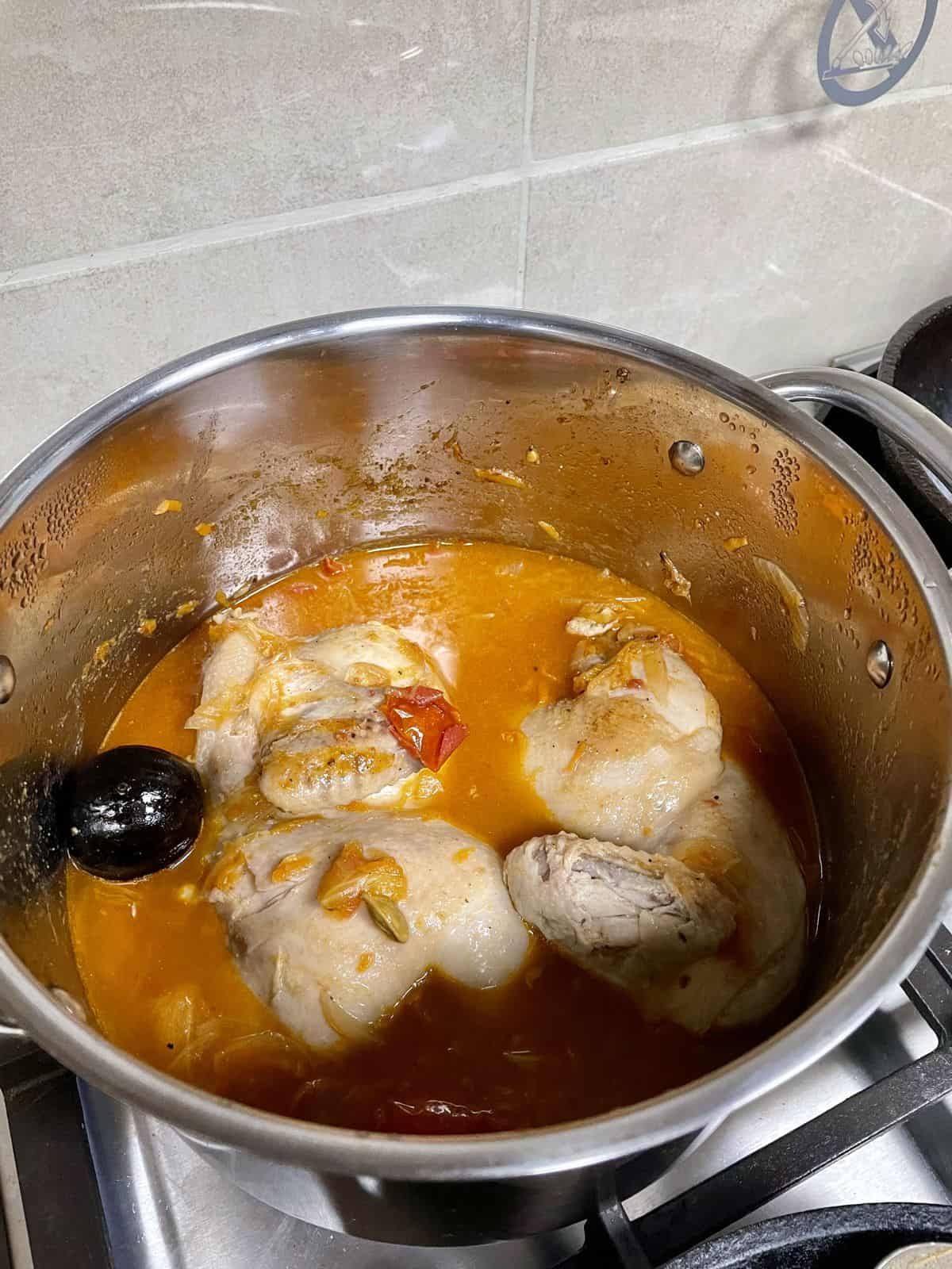 Boiling halved chicken in kabsa broth.