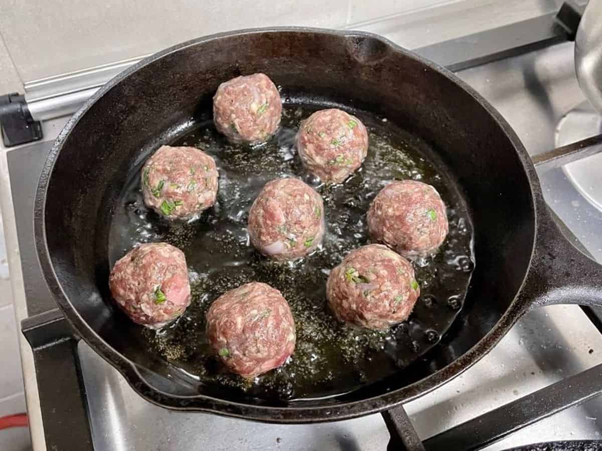 searing meatballs in a cast iron skillet