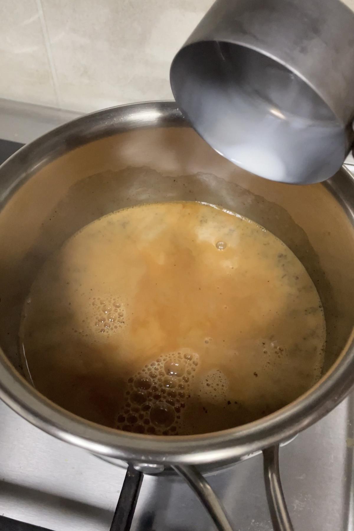 adding milk to boiled tea