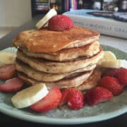A stack of buttermilk pancakes served with fresh berries and banana slices.
