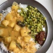ash gourd curry poured over a bed of white rice with green beans and pickle in the side