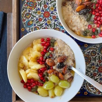 a bowl of oatmeal porridge with brown butter, fruits and nuts