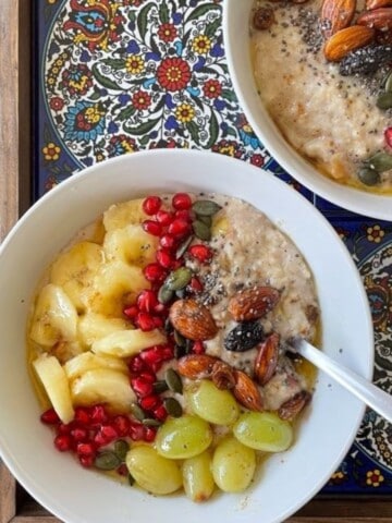 a bowl of oatmeal porridge with brown butter, fruits and nuts