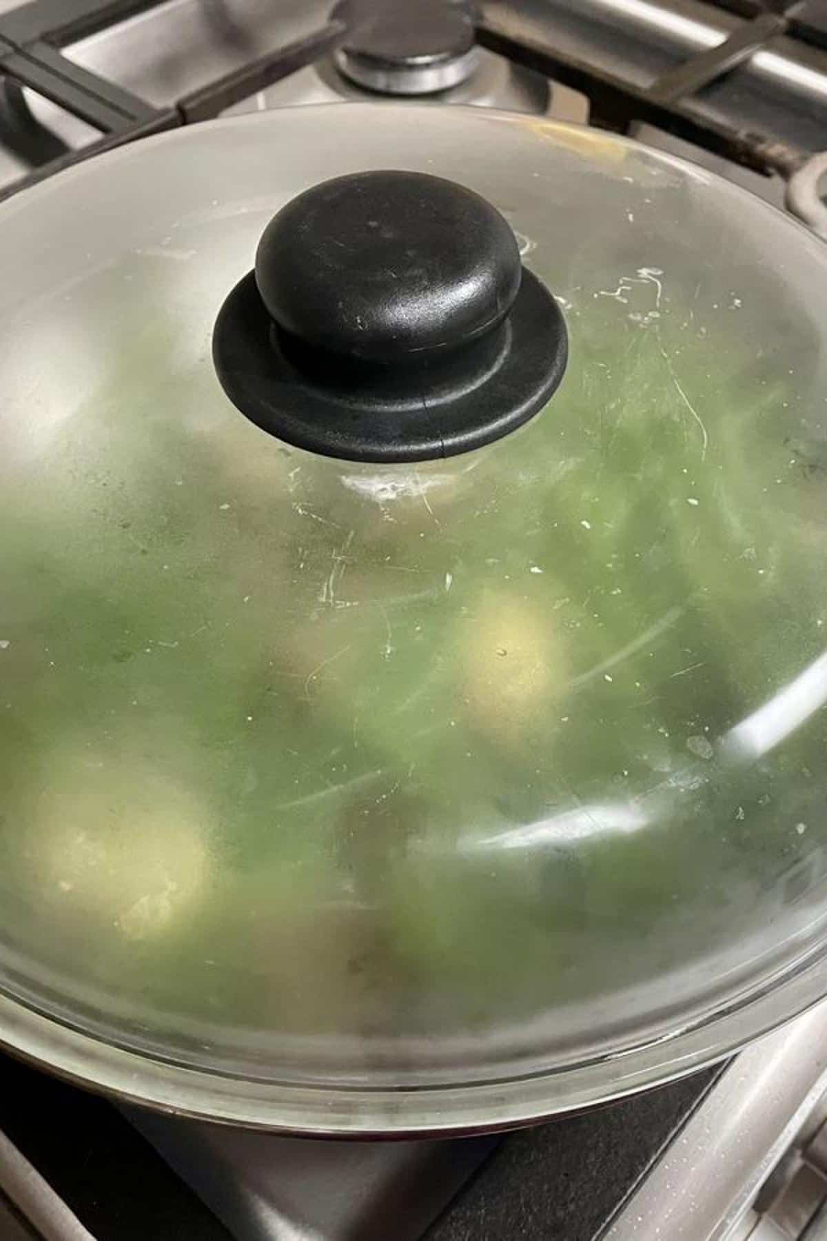 The skillet is covered with a glass lid.