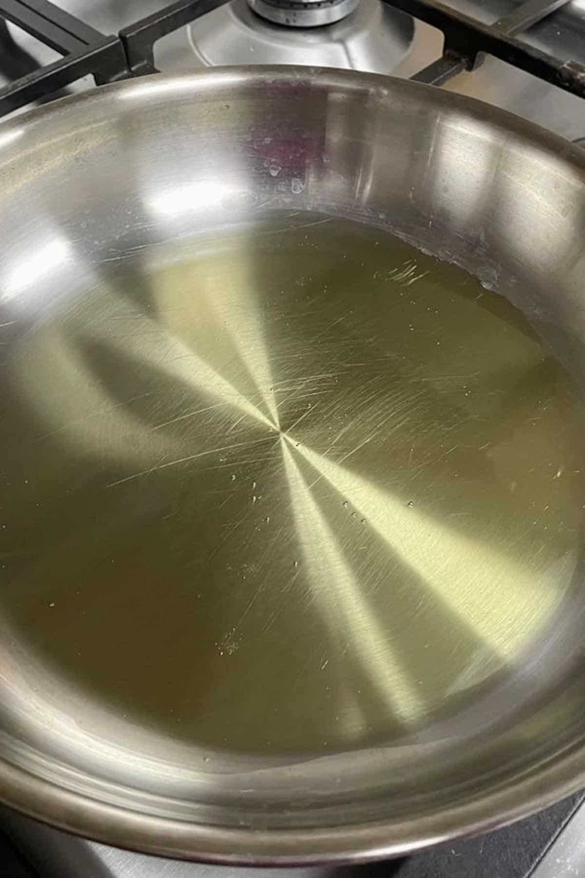 A stainless steel skillet with olive oil.
