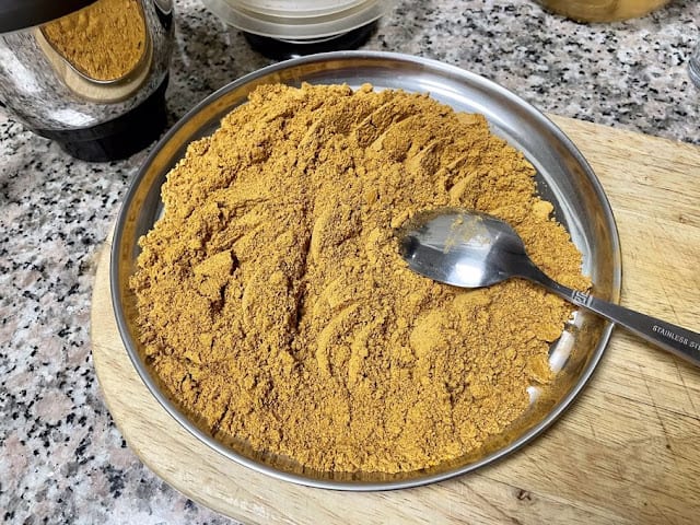 ground sambar powder being spread in a plate to cool