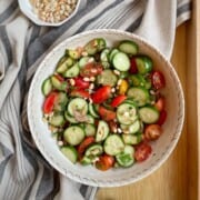 A bowl of cucumber salad with a small bowl of roasted peanuts by the side.