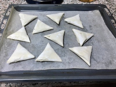 wrapped samosas on a parchment lined baking sheet