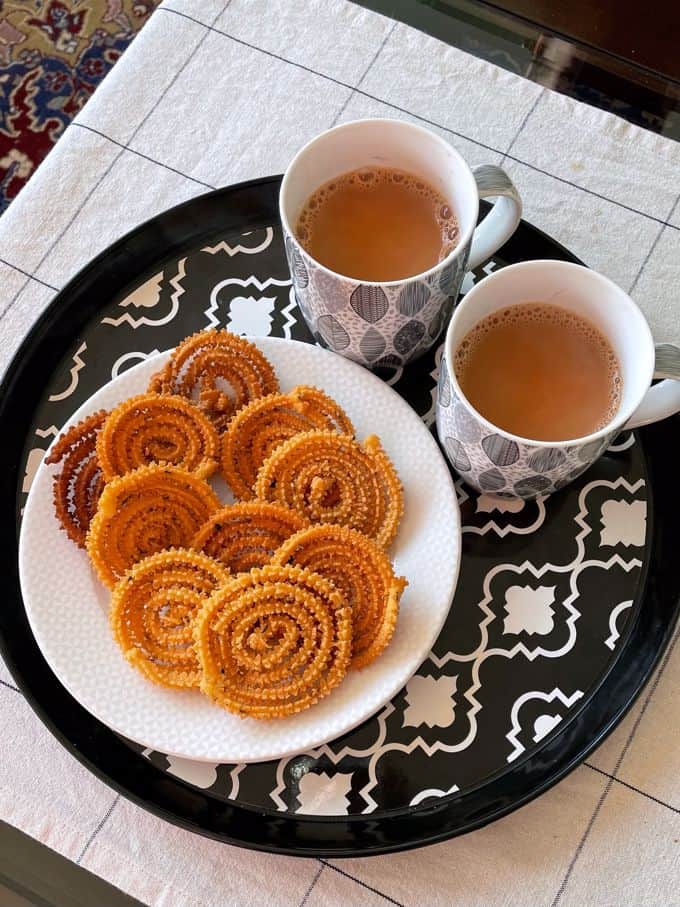 a plate of besan murukku served with two cups of chai