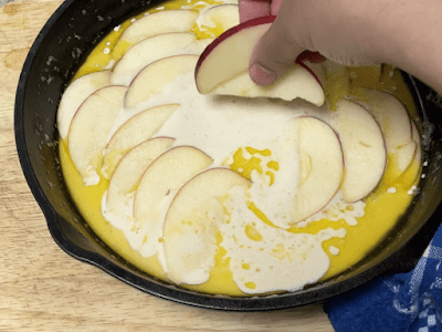 scattering apple slices over the batter