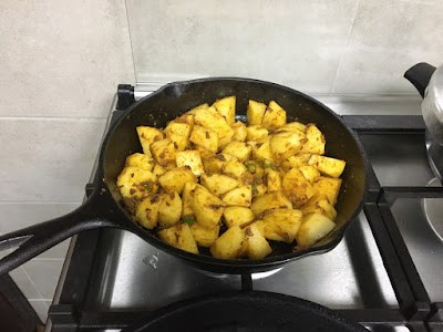 potato cubes being pan-cooked in a spice blend