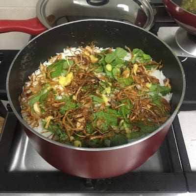 pot of rice topped with fried onions and mint leaves