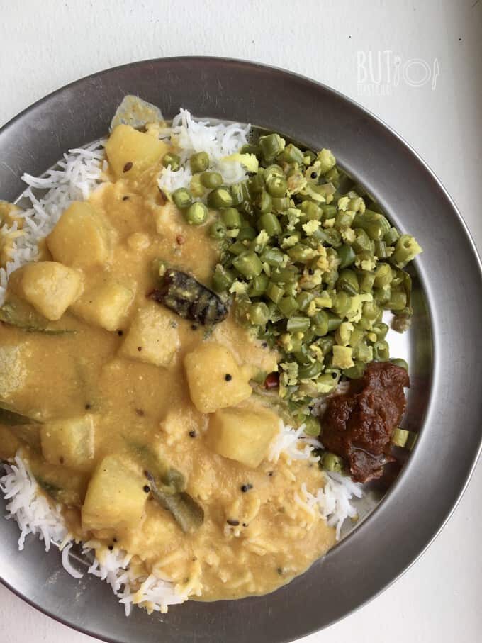 ash gourd curry poured over a bed of white rice with green beans and pickle in the side