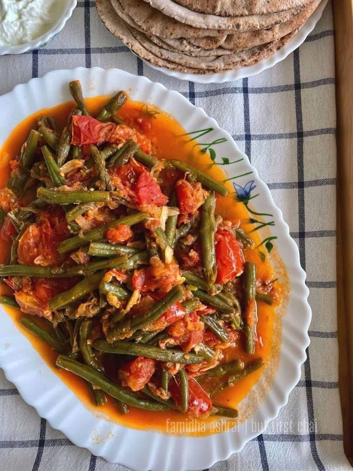 green beans in tomato stew served along a stack of pita