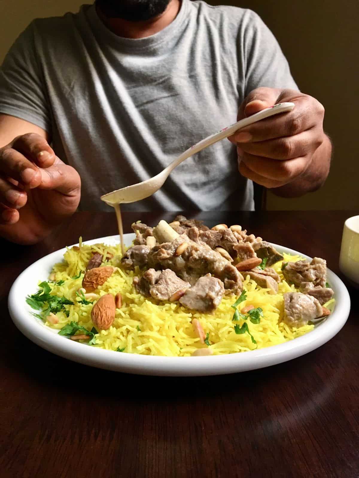 pouring jameed sauce over yellow rice