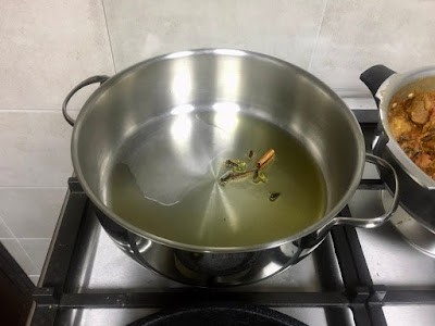 Frying whole spices in ghee in a wide deep pot. 