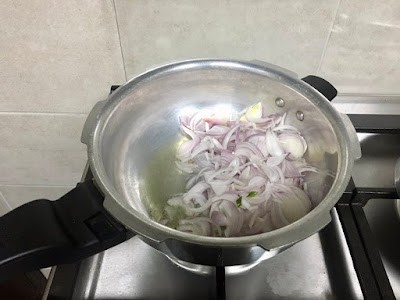 sliced onions in oil in a pressure cooker pan