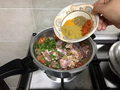 adding ground spices to make mutton biryani 