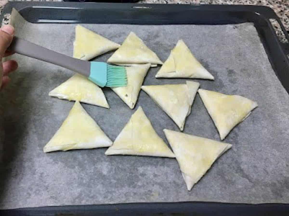 brushing the samosas with melted ghee