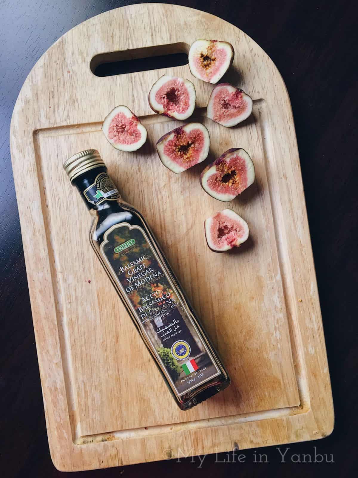 sliced fig and a bottle of balsamic vinegar on a cutting board.