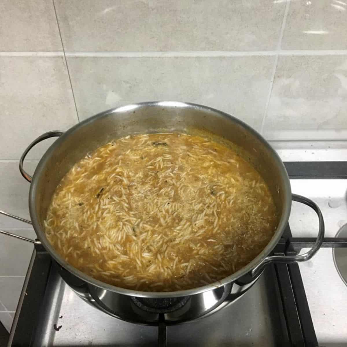 Cooking kabsa rice in chicken broth.