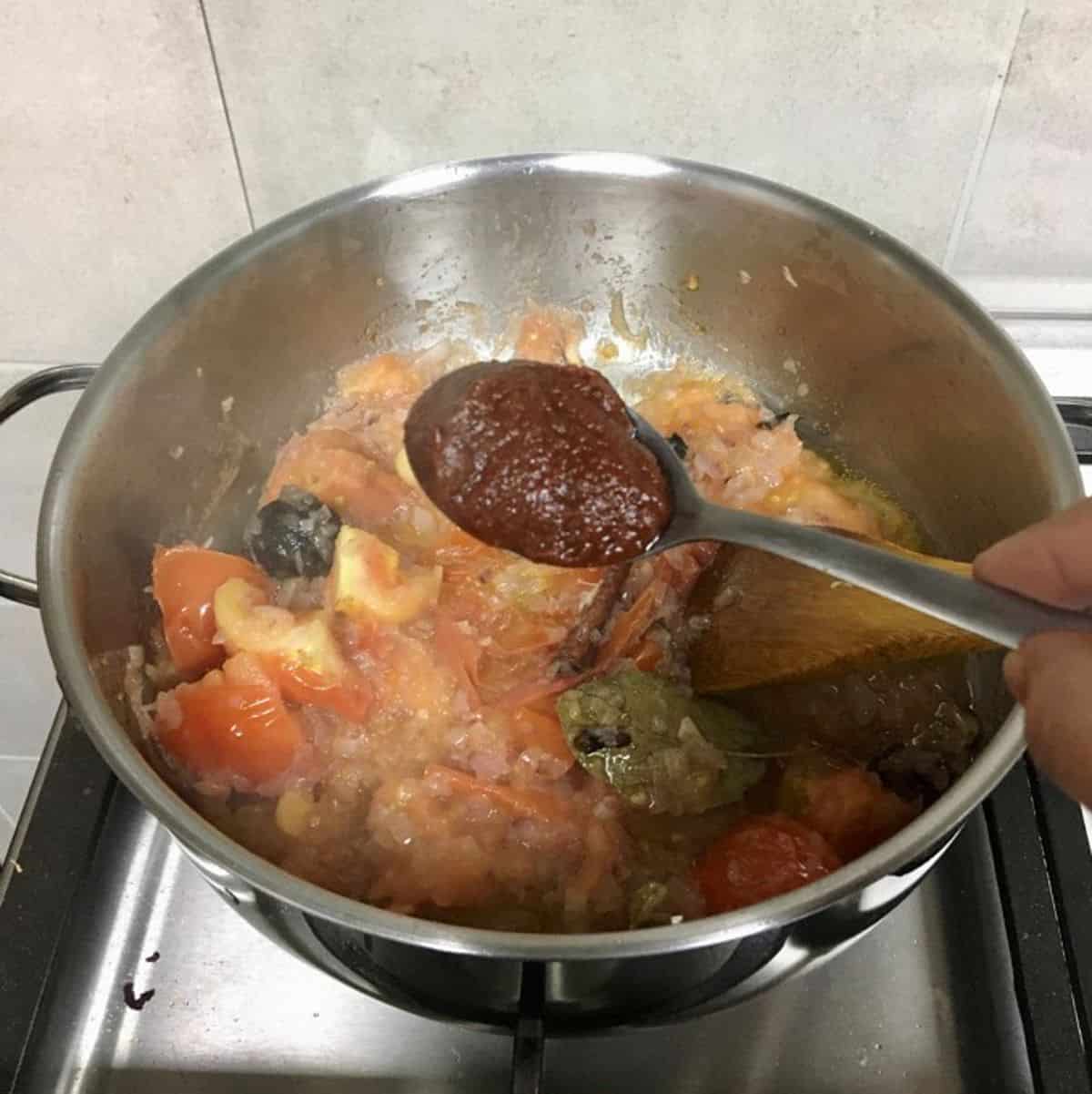 Adding a spoon of tomato paste.