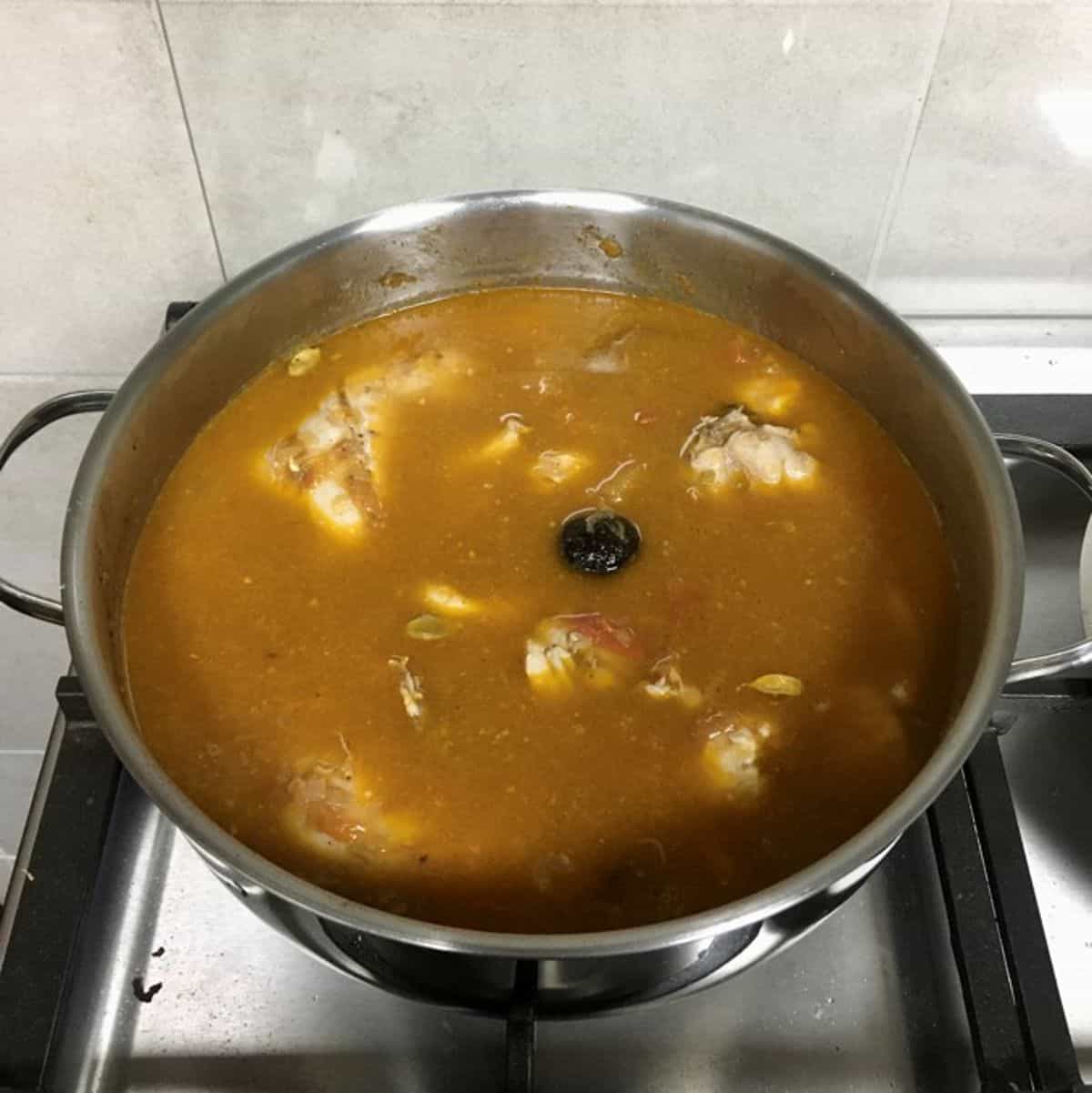 A pot of chicken and tomato rich broth.