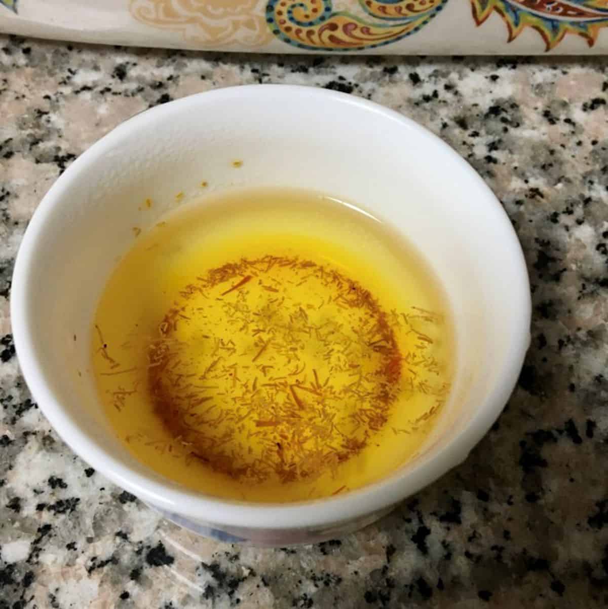 saffron infused water in a small white bowl.
