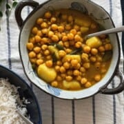 chickpeas and potato curry served in a bowl along side white rice