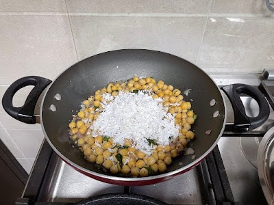 finishing off with grated cocont on warm chickpea sundal