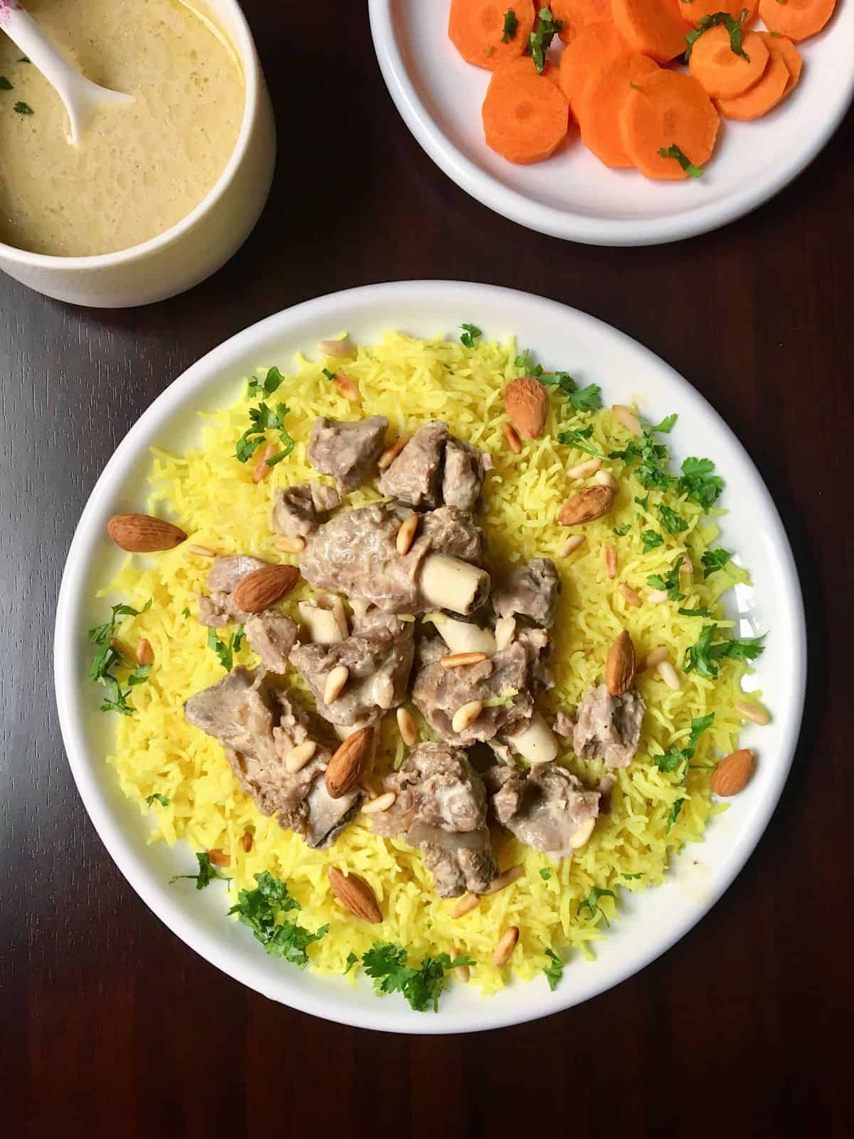 yellow rice topped with lamb meat pieces and almonds