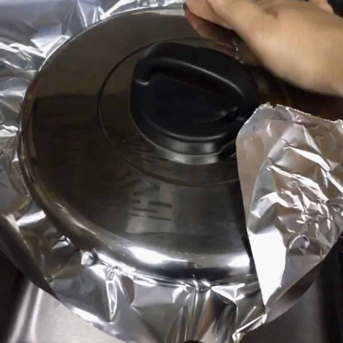 pot being covered with foil and then lid