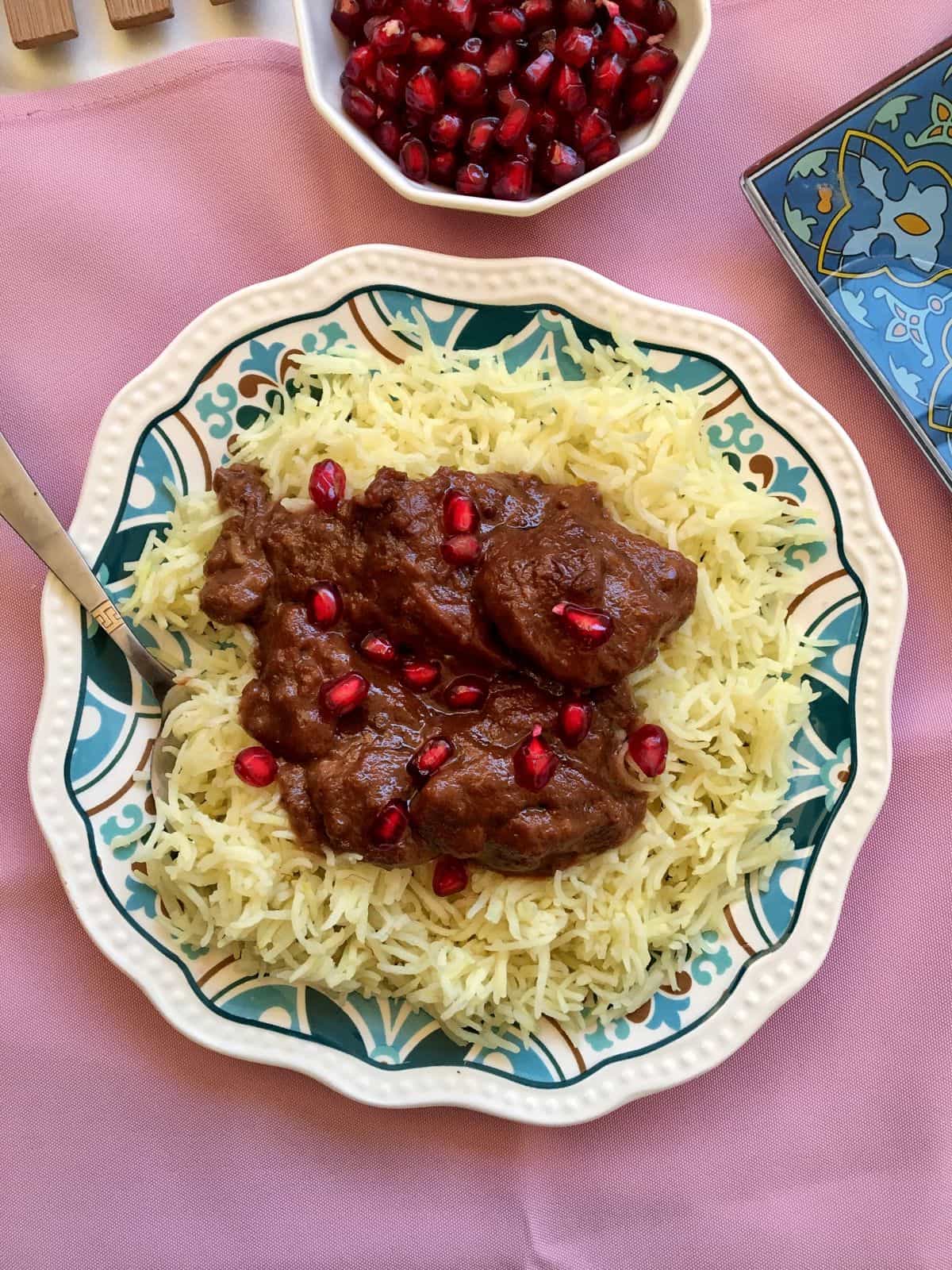 A plate of Khoresht Fesenjan served on top of saffron rice. 