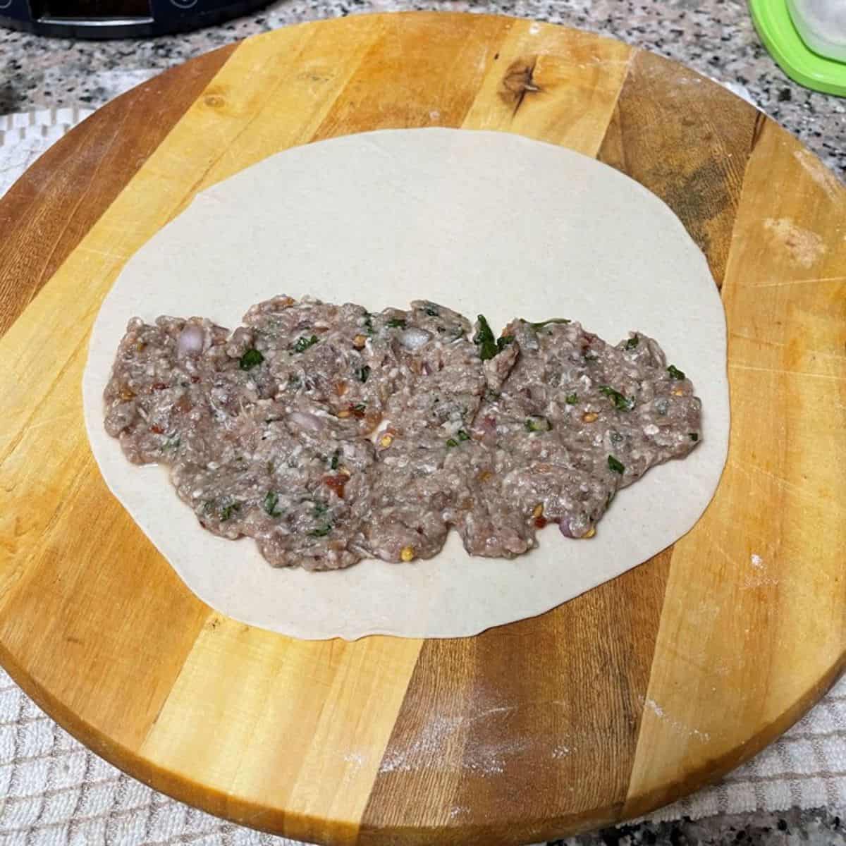 Thinly rolled dough with meat stuffing on one side.