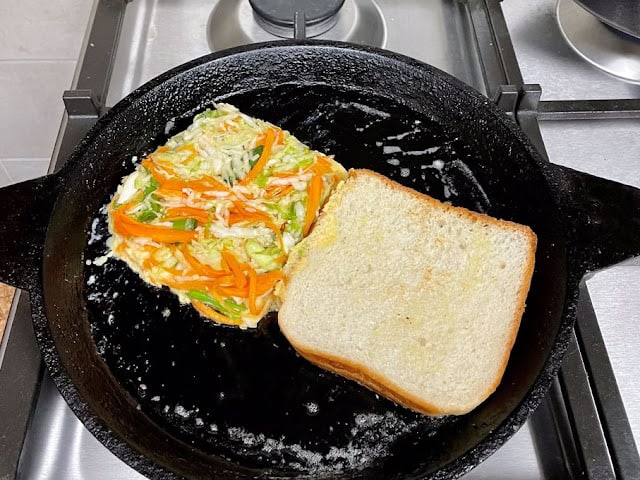 pan with a shaped cabbage egg patty beside a slice of bread