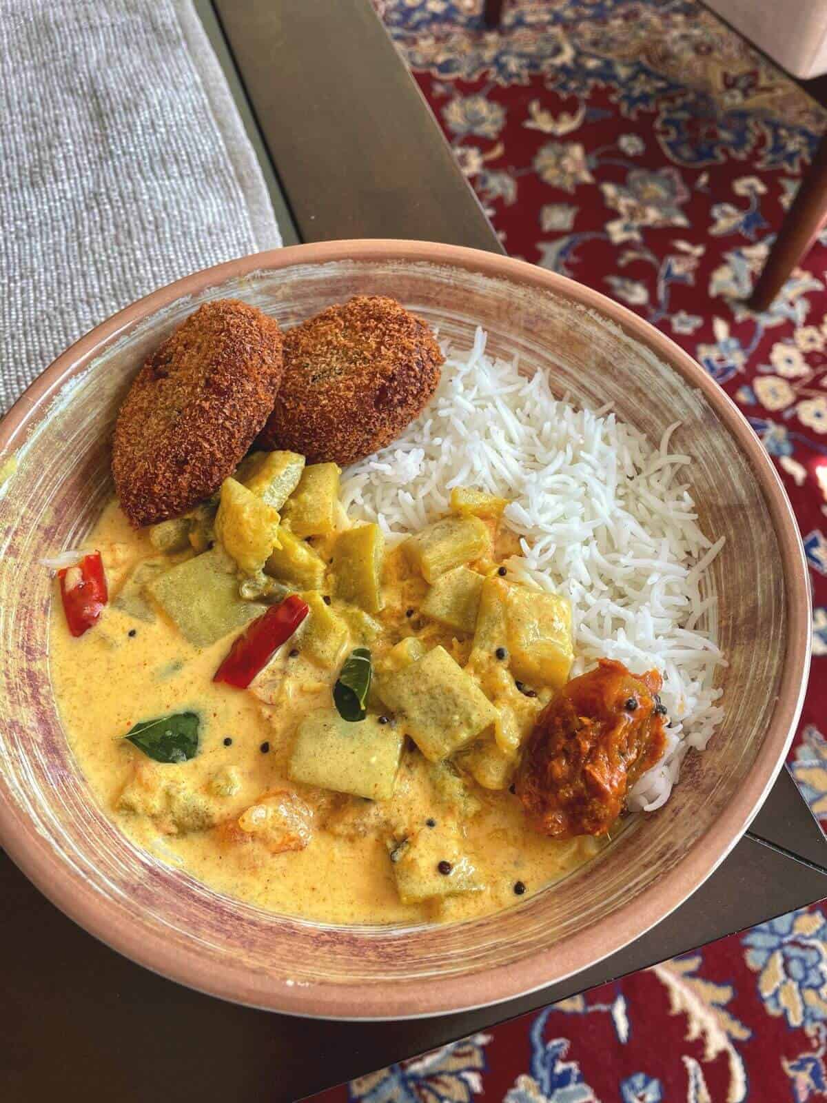 bottle gourd in yoghurt curry with white rice served in a bowl with two kerala style chicken cutlets