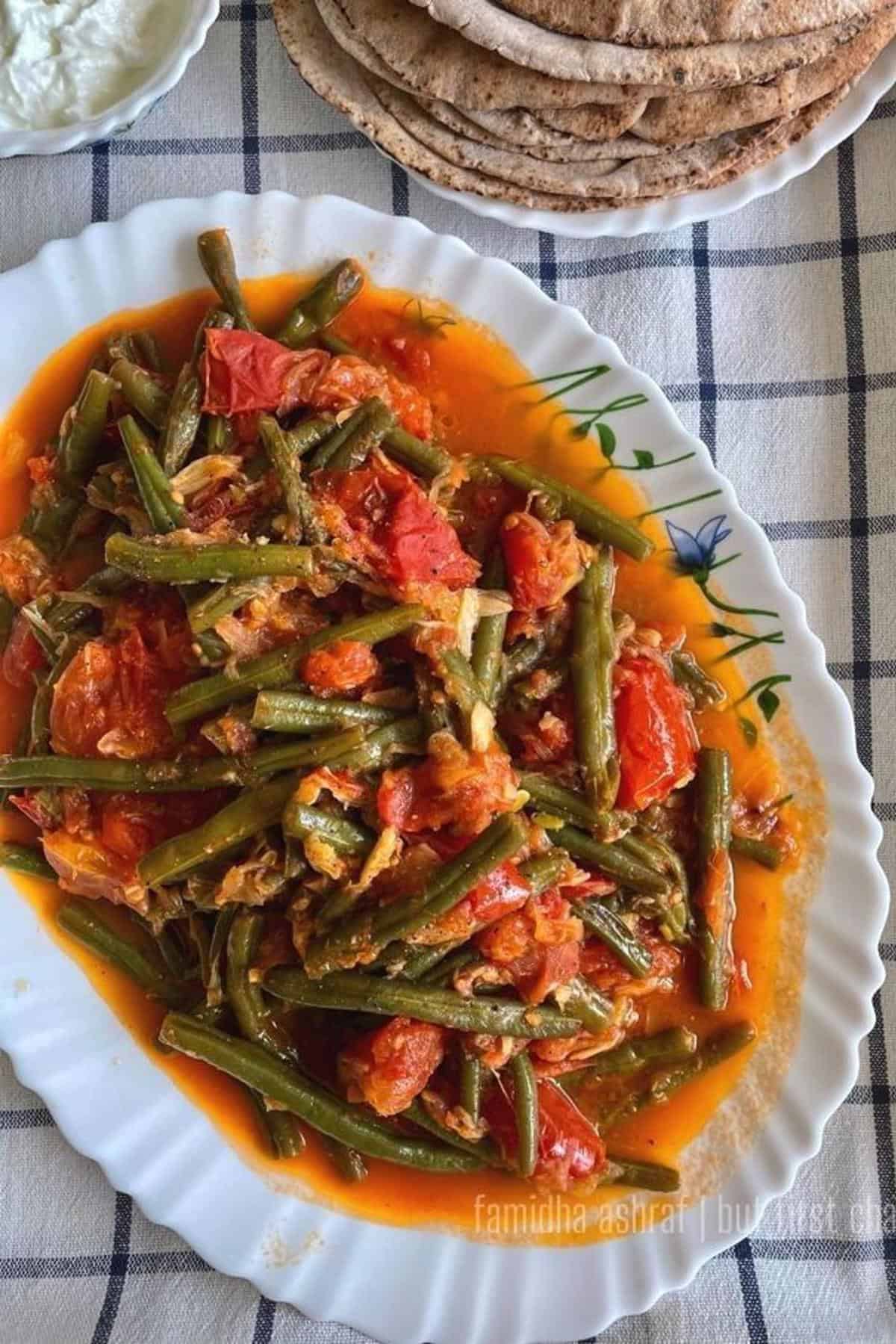 green beans in tomato stew served along a stack of pita