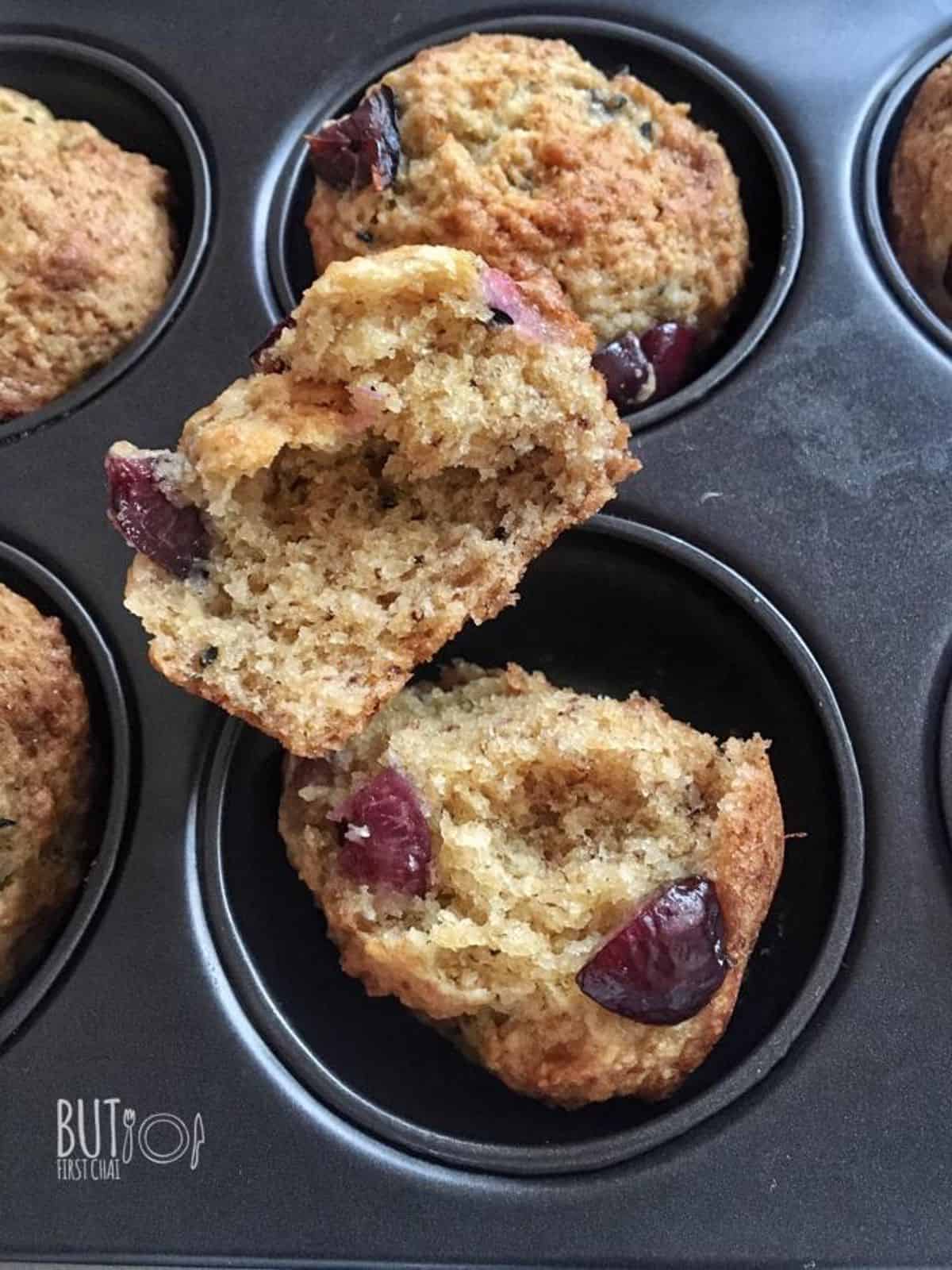 A halved eggless banana muffins with cherries in a muffin tray.