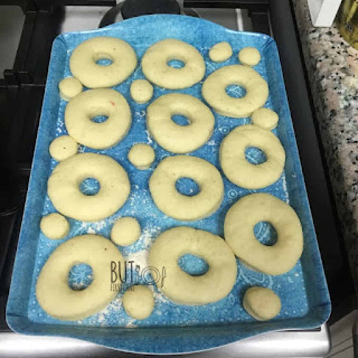 cut out doughnuts and donut holes on a floured tray ready for second rise.