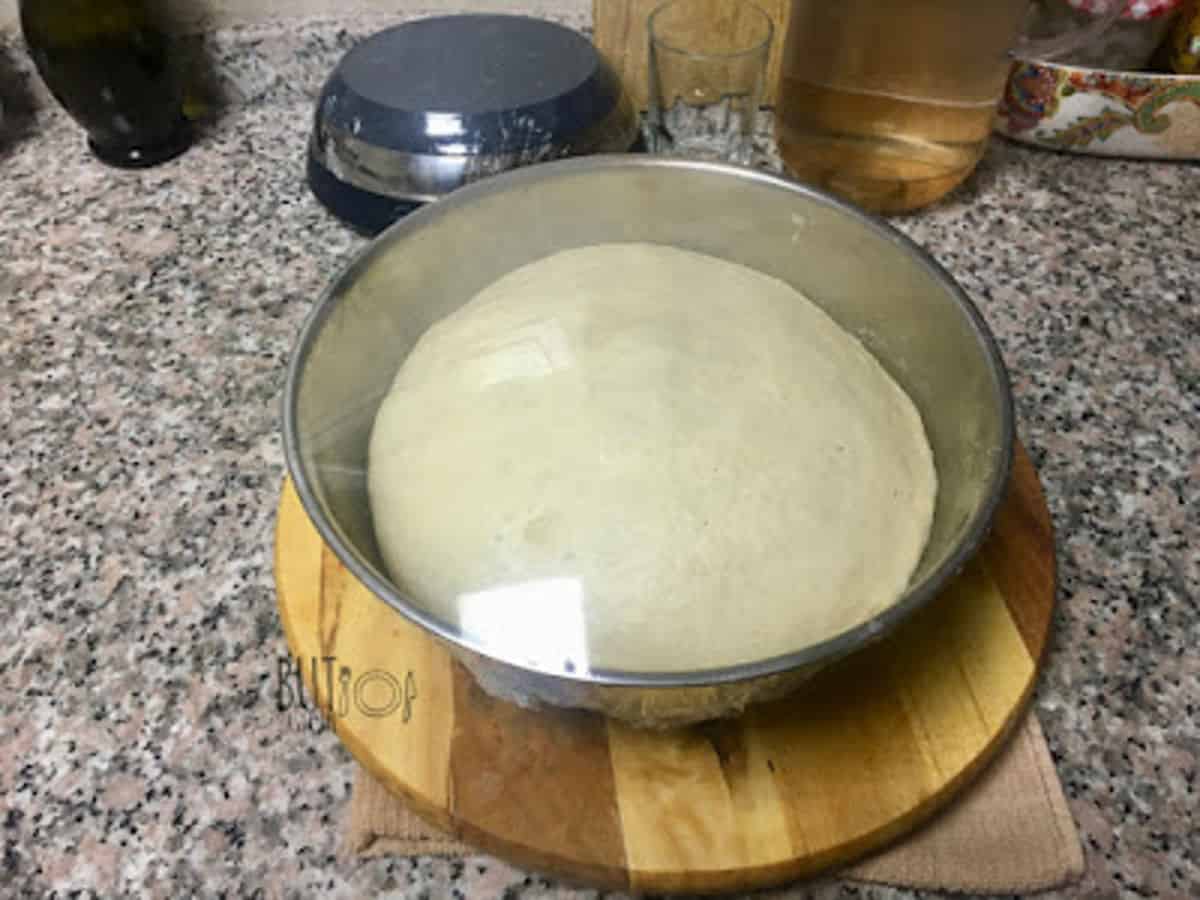 fully risen dough in a cling wrapped bowl.