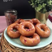 rose glazed yeast donuts stacked on a plate garnished with dried rose petals.