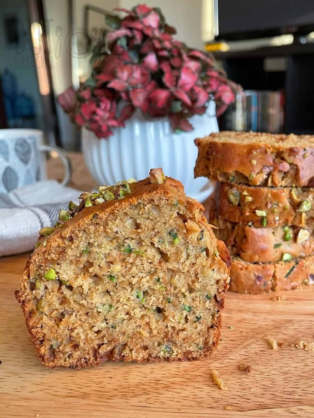 zucchini bread loaf cut side with a stack of sliced bread behind.